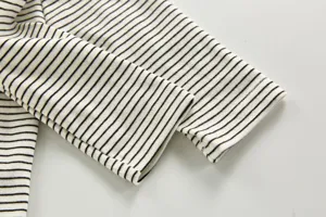 Close-up detail of infant black and white striped top sleeve, knit fabric texture.