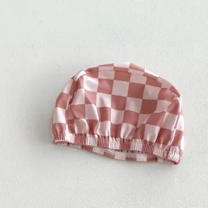 Bonnet de bain bébé à carreaux rose et blanc en détail, accessoire de maillot mignon, bord élastique.