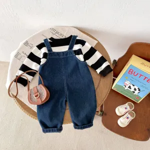 Joli ensemble d'automne pour bébé avec sweat rayé noir et blanc et salopette en denim.