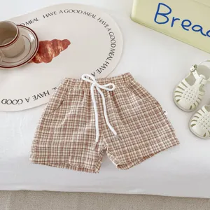 Vue détaillée de shorts d'été à carreaux pour enfants avec cordon de serrage et tissu doux.