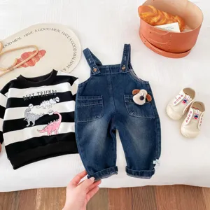 Vue détaillée du joli ensemble sweat dinosaure et salopette en denim pour bébé avec accessoires.
