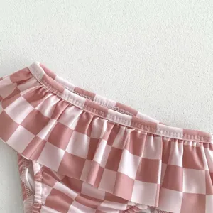 Détail de maillot de bain à carreaux roses pour bébé fille, joli design à volants doux.