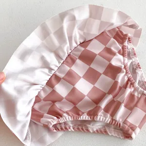 Gros plan détail d'un bas de maillot de bain bébé à carreaux roses et blancs avec jupe à volants.