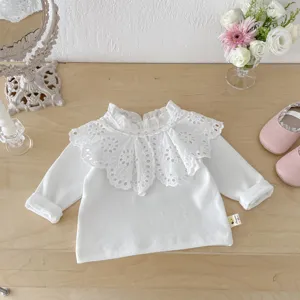 Nahaufnahme Detail des weißen Langarmtops für Babymädchen mit wunderschönem Spitzenkragen.