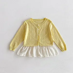 Detailed view of kids knit cardigan, yellow top with white hem, delicate knitwear.