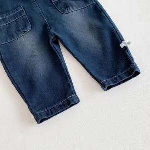 Détail de salopette en jean pour bébé, lavage fondu foncé avec poches et belles coutures.