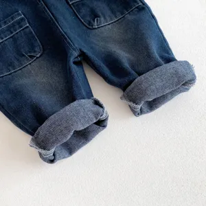 Gros plan détaillé de pantalon en jean pour bébé avec revers aux jambes et poches pratiques.
