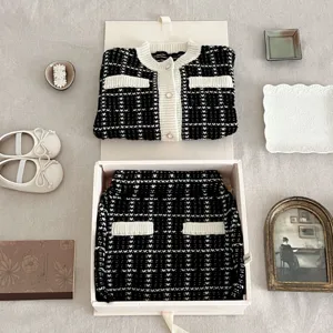 Detailed view of the infant black and white tweed knit cardigan and skirt set for girls.