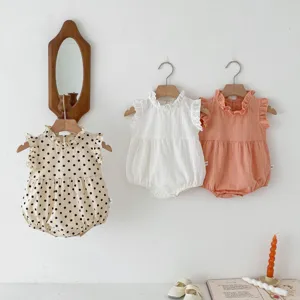 Detail shot of cute baby rompers in solid and polka dot patterns hanging on wooden hooks.