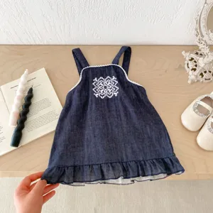 Detalle de vestido tirantes vaquero bebé, bordado de pecho blanco y dobladillo.