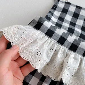 Baby clothing detail shot showing black white checkered fabric and delicate white lace ruffles.