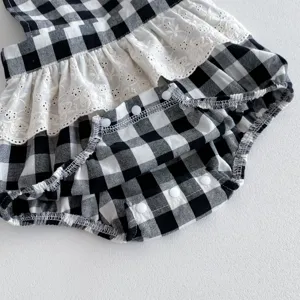 Black and white gingham baby romper detail, featuring white lace ruffles and convenient snap buttons.