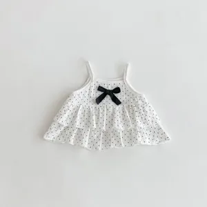 Detail of cute baby girl polka dot camisole with black bow and layered ruffles, soft fabric.