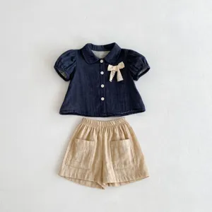 Conjunto de verano para niñas pequeñas, blusa azul oscuro con lazo y shorts beiges.