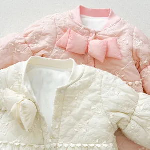 Cute baby quilted winter jacket detail shot, warm fleece-lined infant clothes with big bow accent.