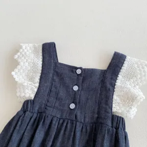 Primer plano de los detalles del vestido de bebé con mangas de encaje blanco y botones.