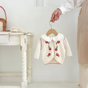 Close-up detail of cute toddler knit cardigan vest with strawberry embroidery and collar.