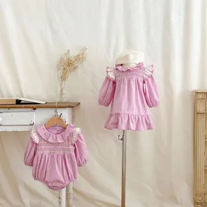 Vista dettagliata di tutina rosa dolce e abito per bambina con volant arricciati.