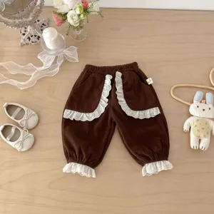 Detailed view of cute toddler girls brown corduroy pants with white lace ruffles and cuffs.