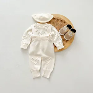 Close-up details of baby knit sweater set, cream white infant wool outfit flat lay.