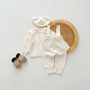 Baby winter knitwear set detail, cozy beige sweater overalls hat and cute shoes outfit.