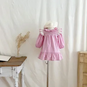 Abito rosa a maniche lunghe per bambina piccola con colletto con volant bianchi e berretto.