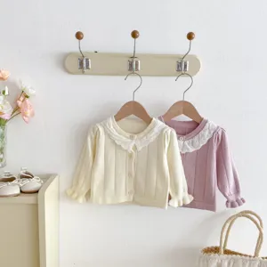 Close-up detail of infant knit cardigan with delicate lace collar, sweet baby apparel scene.