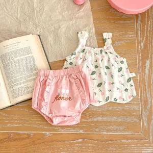 Dettaglio del completo estivo da neonata con top floreale e pantaloncini rosa con volant.