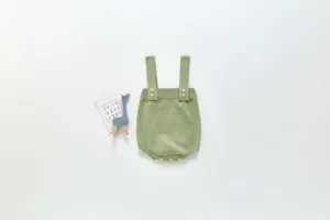 Détail de barboteuse tricotée pour bébé, body uni à bretelles avec boutons en bois.