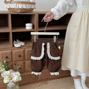 Toddler girl brown corduroy pants detail, cute white lace ruffles on pocket and cuff.