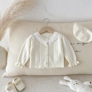 Detail view of infant beige knit cardigan featuring delicate lace collar and front button closure.