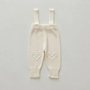Knit baby strap pants detail, soft off-white infant knitwear clothing, cute baby apparel.