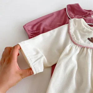 Détail de barboteuse à manches longues en velours côtelé pour bébé fille, joli col brodé.