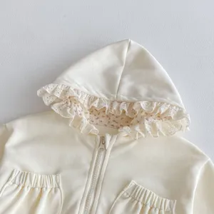 Close-up detail van baby crèmekleurige hoodie, bloemenvoering en delicate kanten rand.