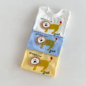Infant short-sleeve t-shirt detail showing the 3D lion plush patch and colorful stacked cotton shirts.
