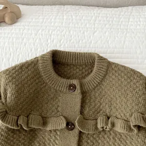 Vista dettagliata del cardigan in maglia per neonato con volant, scollo tondo e bottoni.
