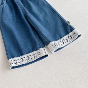 Girls blue denim pants detail, featuring delicate white lace cuffs and cute logo tag.