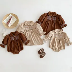 Infant corduroy dress romper detail featuring delicate smocked embroidery and cute long sleeves.