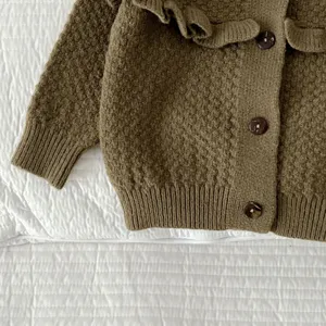 Primo piano di un cardigan in maglia per neonato con colletto con volant e dettagli.