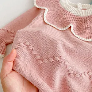 Detailansicht des Strickspielanzugs für Babys, rosa Pullover mit großem Kragen und süßen Noppen.