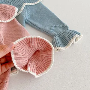 Detailaufnahme des Babystramplers mit handgemachten Bollen, Rüschenkragen und Struktur.