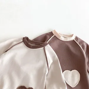 Baby Langarm Waffelstrick Pullover Detail mit süßem Herz-Aufnäher und Kontrastbesatz.