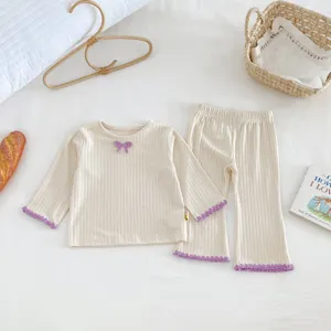 Close-up detail of infant ribbed knit top and flared pants set with purple lace trim and bow.