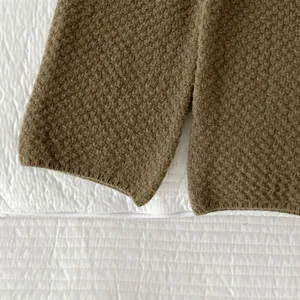 Primo piano sui dettagli di manica e orlo del top in maglia per neonati, tessuto marrone.