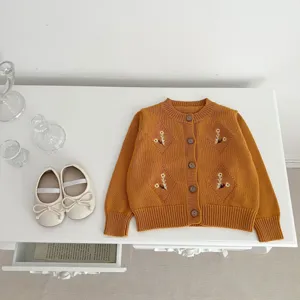 Baby girl knit cardigan sweater with floral embroidery and cute white shoes for autumn wear.