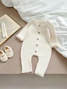 Detailaufnahme der gerippten Babystrampler Textur mit Holzknöpfen, kuschelige Frühlingskleidung.