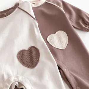 Nahaufnahme Detail des Baby Waffelstrick Langarm Stramplers mit niedlichem Herz Flicken.