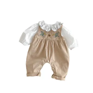 Cute baby girl clothing set featuring white ruffled blouse and embroidered khaki overall jumpsuit.