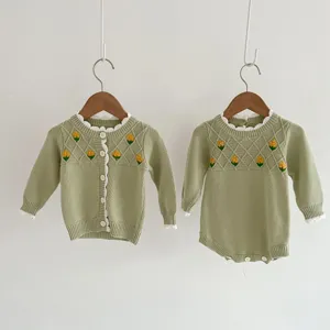 Detail shot of baby knit cardigan and romper with cute yellow flower embroidery in soft green.
