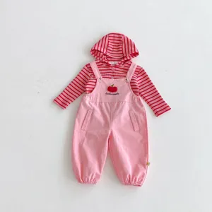 Primer plano detalle del conjunto de peto rosa para niña con bordado de manzana.
